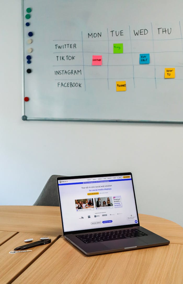 digital-01 A modern office setup featuring a laptop and a whiteboard schedule for social media platforms.